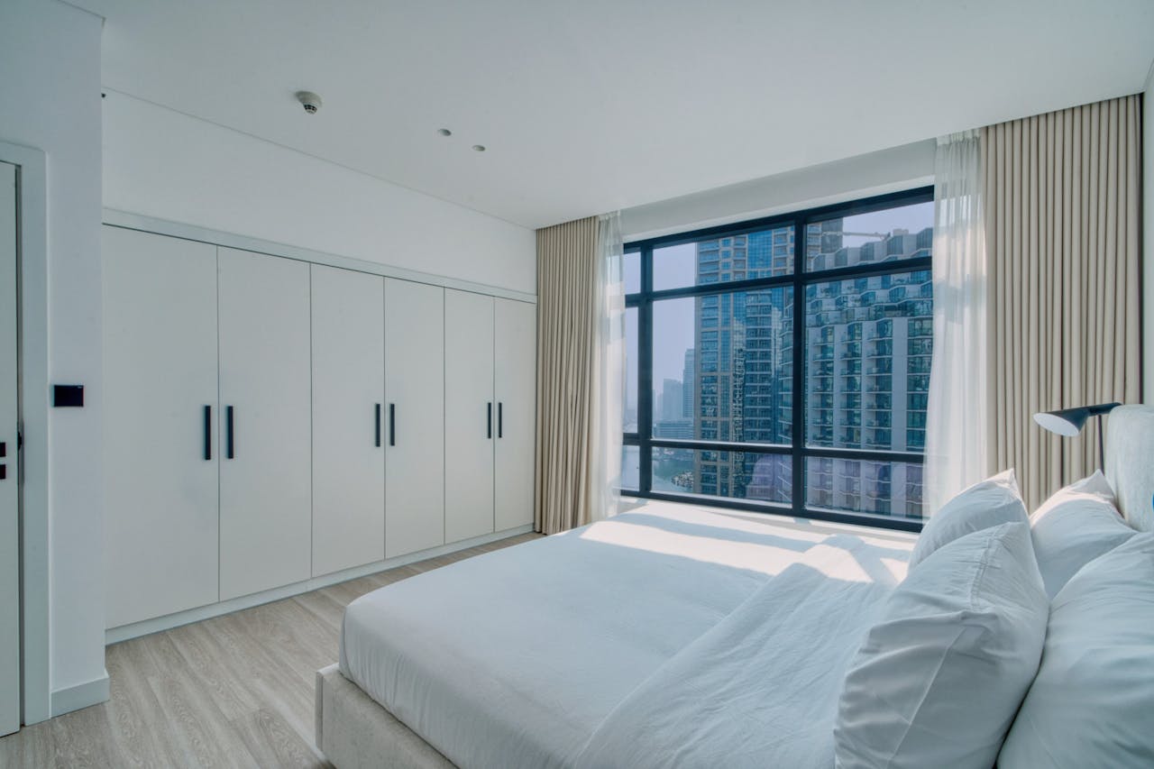 Bright, minimalist bedroom with cityscape views and contemporary furniture.